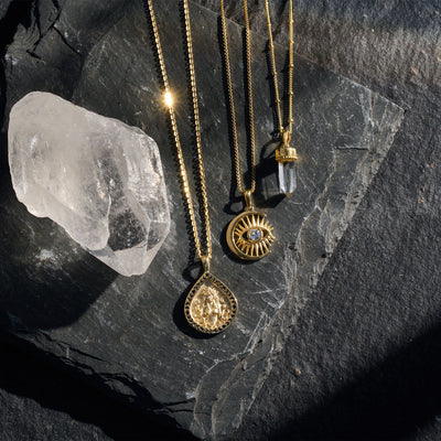 A collection of Awe Inspired Crystal Quartz Amulets on top of a stone.