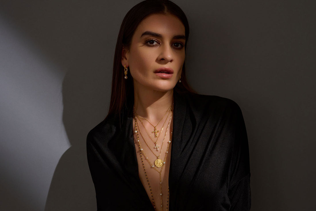 Model wearing Mary Magdalene Coin Pendant Necklace, Enamel Cross Necklace, Pearl Cross Necklace, Pearl Lariat Necklace and a Black Enamel Chain