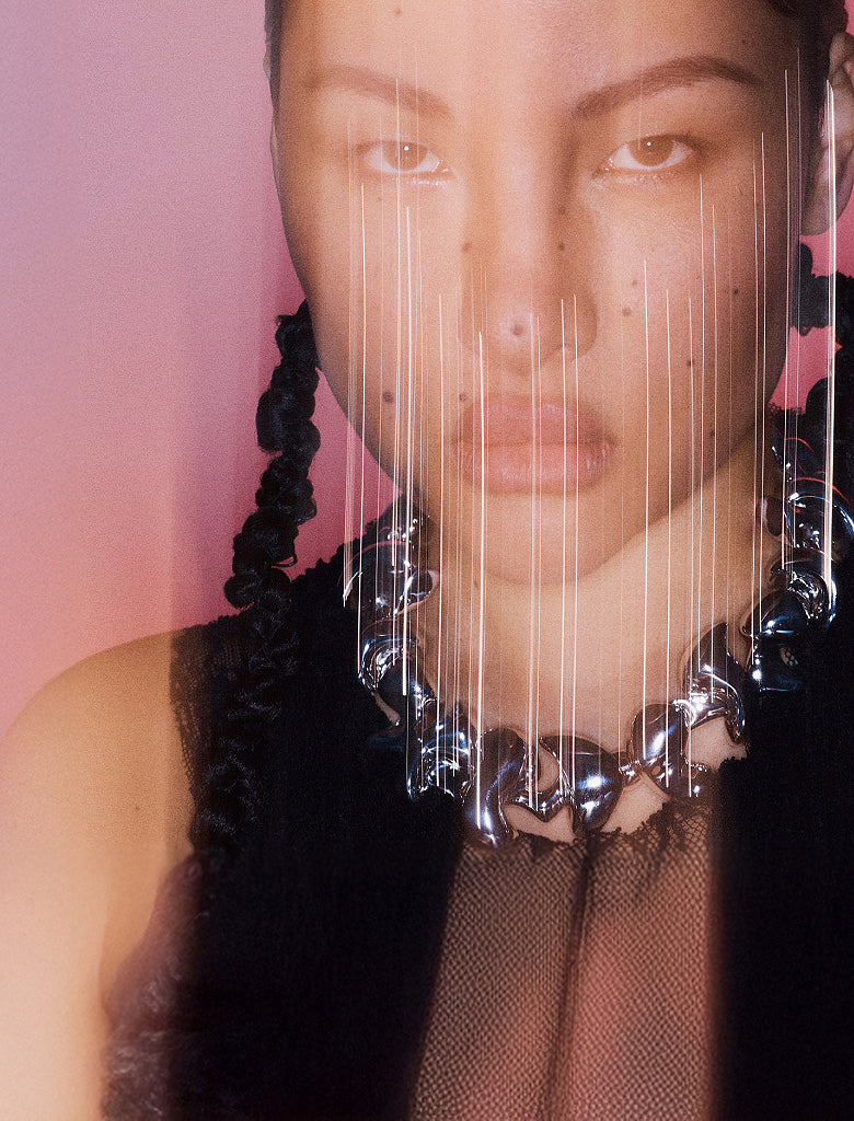 Product image of A person wearing layered silver necklaces and an earring. The necklaces feature a sun and moon pendant, a shell pendant, and another abstract pendant. The person is wearing a black shirt.