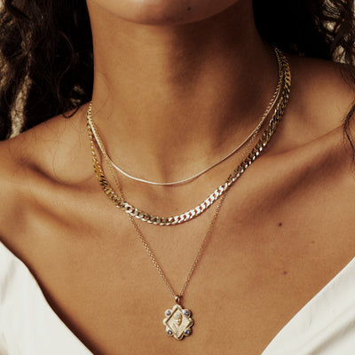Model wearing Queen Esther Pendant with a border of blue sapphires in gold vermeil