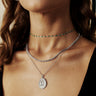 A woman wearing a necklace with the Catherine The Great Pendant with emeralds by Awe Inspired in sterling silver