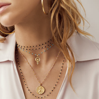 A woman wearing Black, Blush and Turquoise Awe Inspired Colored Enamel Necklaces layered with standard Aphrodite pendant. 