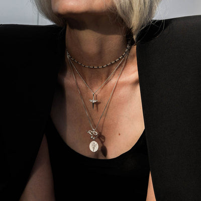 A woman with blond hair wearing the Flying Dagger Amulet by Awe Inspired necklace.