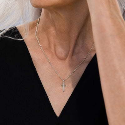 A woman wearing a Cross Amulet necklace from Awe Inspired.