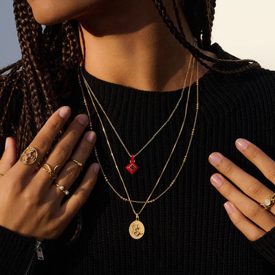 Model wearing Red Aura amulet with ruby gemstone layered with Zodiac Goddess pendant in gold vermeil