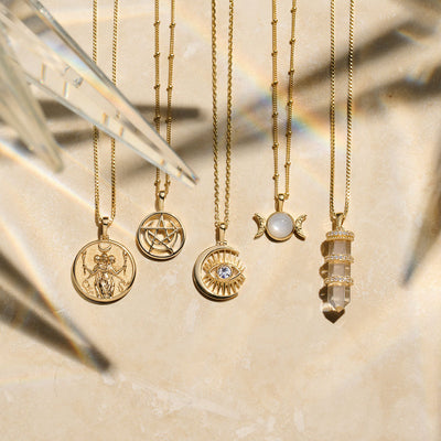 A collection of Awe Inspired Triple Moon Amulet necklaces with different symbols on them.