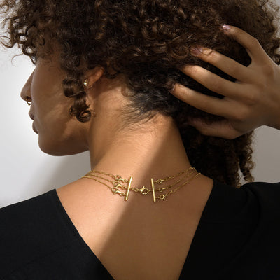 A woman with curly hair wearing an Awe Inspired Three Necklace Layering Tool.