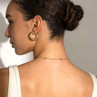 The back view of a woman wearing Awe Inspired gold hoop earrings.