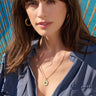 A woman in a blue shirt is posing for a photo with an Awe Inspired chain necklace.