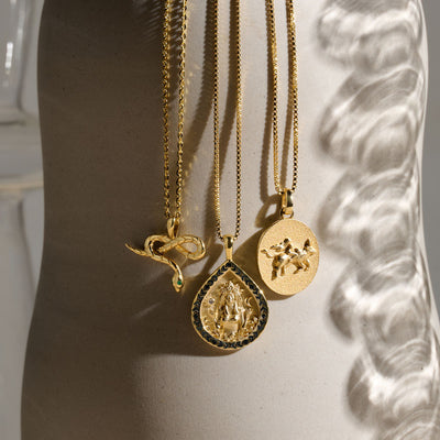 Ala pendant on a box chain paired with Emerald Eye Snake amulet on a cable chain and Taurus pendant on box chain in gold vermeil