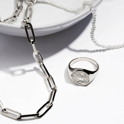 A white Aphrodite Signet Ring with a silver ring and a silver chain from Awe Inspired.