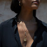 Person wearing a black shirt, gold hoop earrings, and the Lady Buddha Goddess Necklace from Awe Inspired, featuring layered gold pendants that evoke the grace of Lady Buddha.