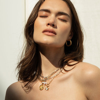 A woman wearing multiple The Collector Necklaces in gold vermeil and sterling silver