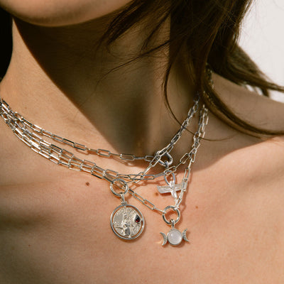 A woman wearing a Triple Moon Amulet necklace by Awe Inspired with a coin and a star.