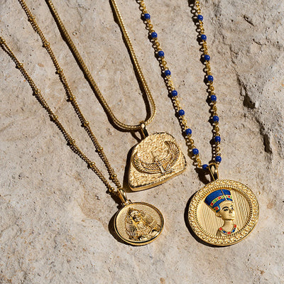 Three Cleopatra Pendant necklaces on a stone. (Brand Name: Awe Inspired)