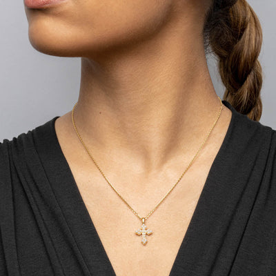 A woman wearing an Awe Inspired Pearl Cross Amulet necklace with diamonds.