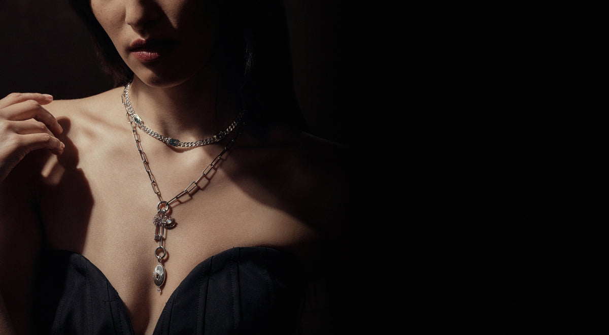 Model wearing layered sterling silver charm necklaces