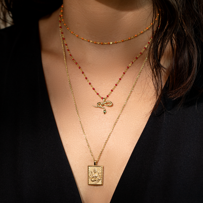 A woman wearing an Awe Inspired gold necklace and a red necklace.