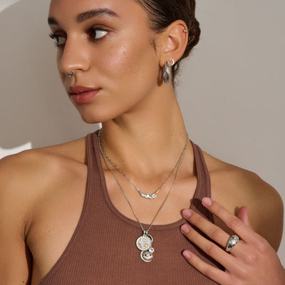 A woman wearing a brown tank top and Awe Inspired's Hedone Pendant necklace.