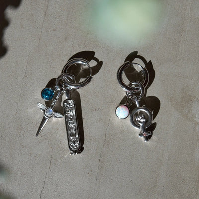 The Collector Earring paired with Blue Topaz Amulet, Min Flying Dagger Amulet, Cartouche Tablet and Woman Power Amulet in sterling silver