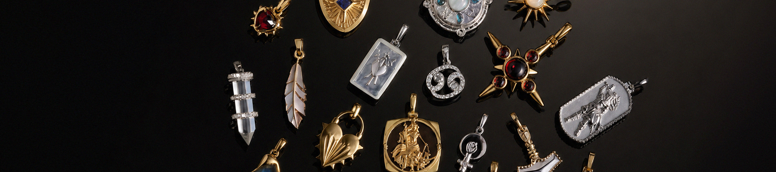 A collection of assorted jewelry pendants and charms displayed on a dark black background. The collection includes various gold and silver-toned pendants with different designs, including a feather, a sword, a scorpion, a shield, and a crescent moon.
