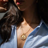 A woman wearing a blue pinstripe shirt and an Awe Inspired Kamala Pearl Halo Necklace Set from the 2024 Election Edition.