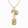 Awe Inspired's Vote Pro-Roe Charm Lariat Necklace Set features a gold necklace adorned with three distinct pendants: a circular symbol with a fist, a coin-shaped charm showcasing a woman's side profile, and a rectangular pendant embossed with an elevated fist. This exquisite piece subtly honors gender equity and serves as an elegant statement for the 2024 Election Edition.