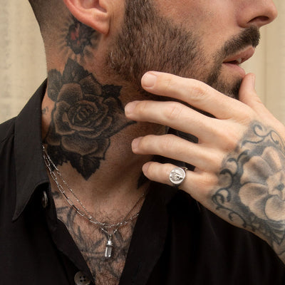 A man with tattoos on his neck and a Crystal Quartz Amulet by Awe Inspired on his finger.