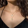 A woman wearing an Awe Inspired Nyx Pendant necklace with a coin on it.