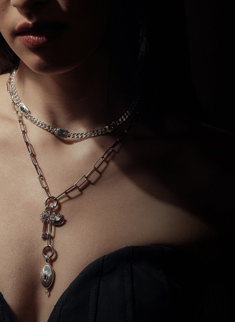 Model wearing layered sterling silver charm necklaces