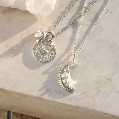 Two Awe Inspired Moonstone Crescent Amulet necklaces with a moon and a star on top of a stone.