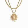 The Special Edition Medusa Layering Set by Awe Inspired, a gold pendant necklace with a Medusa head design and green gemstones for eyes, embodies a powerful totem of protection. The pendant hangs gracefully on a double-chain necklace against a white background.