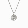 The Mini Aphrodite Necklace by Awe Inspired is a silver pendant necklace featuring a round medallion adorned with an intricate design inspired by Aphrodite, the Goddess of Love. The fine box link chain exudes sensuality in every detail.