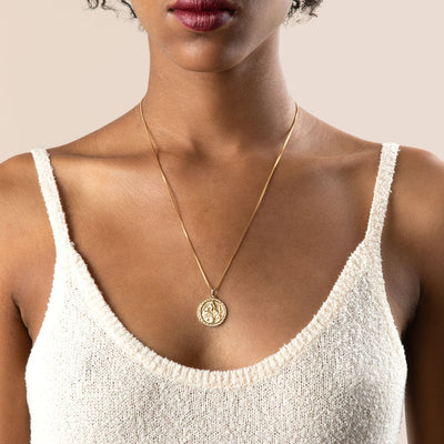 A woman wearing a white tank top and an Awe Inspired Freya Pendant necklace.