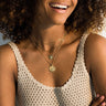 A woman with curly hair is smiling while wearing an Awe Inspired Harriet Tubman Pendant.