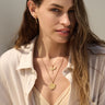 A woman wearing an Awe Inspired Winged Torch Amulet necklace and a white shirt.
