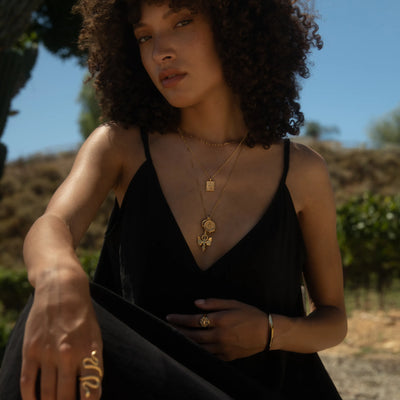 Model wearing Nemesis pendant, Mini Lilith tablet and Winged Torch Amulet in gold vermeil