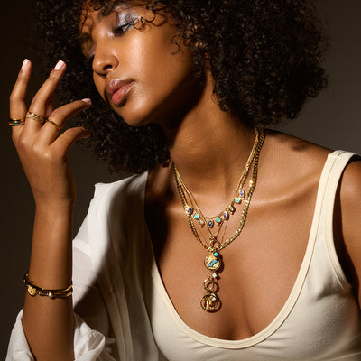 Model is wearing a layered collector set featuring Yemaya pendant in gold vermeil, Iris pendant in gold vermeil, opal drop neacklace in gold vermeil, and curb chain in gold vermeil