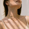 A woman wearing an Awe Inspired Lapis Turquoise Choker Necklace layered with Orbit Chain and Yemaya pendant in gold vermeil