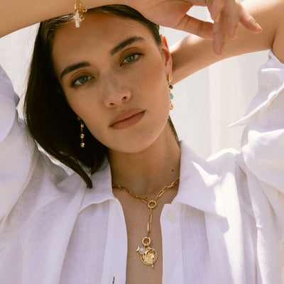 A woman wearing a white shirt and Awe Inspired Triple Moon Amulet jewelry.