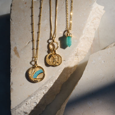 Three Awe Inspired Iris Pendant necklaces on a stone.