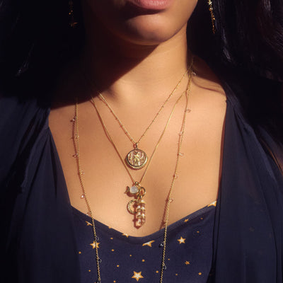 A woman wearing a Triple Moon Amulet necklace by Awe Inspired.