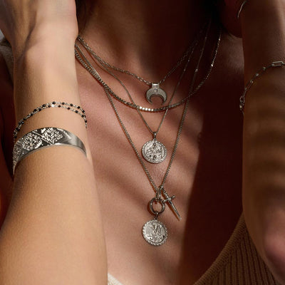 A woman wearing several Awe Inspired Freya Pendant necklaces and bracelets.