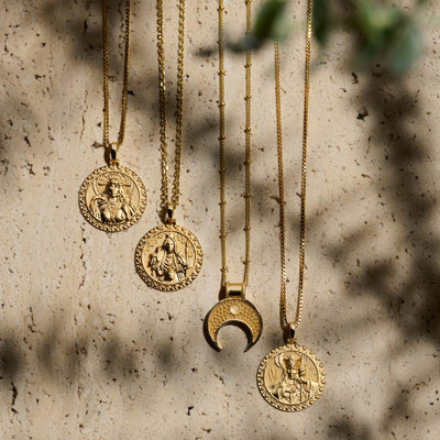 A group of Awe Inspired Frigg Pendant necklaces hanging on a stone wall.