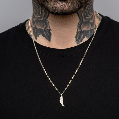 A man with tattoos wearing a necklace with the Wing Amulet by Awe Inspired.