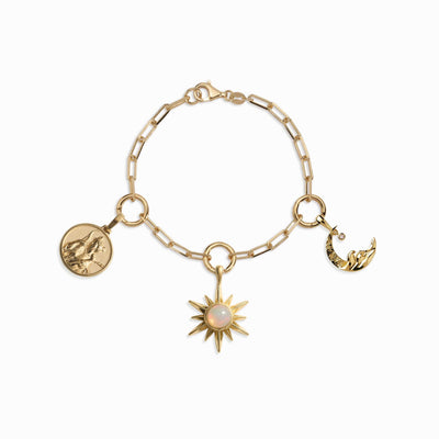 The Cosmic Euphoria Charm Bracelet by Awe Inspired is a gold chain bracelet adorned with three distinct charms: a round coin, an Opal Sun exuding warmth, and a Diamond Moon embodying cosmic euphoria.