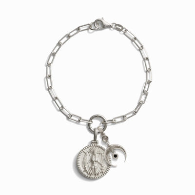 The Awe Inspired Inverted Moon Charm Bracelet features a silver chain with a round pendant engraved with a figure and adorned with a black moon charm, symbolizing the essence of Lilith.