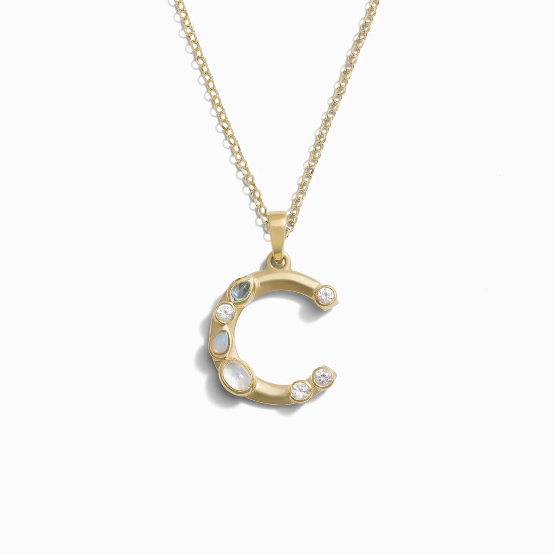 The Gold Gemstone Initial Necklace from Awe Inspired features a pendant shaped like the letter C, adorned with multiple bezel-set gemstones.
