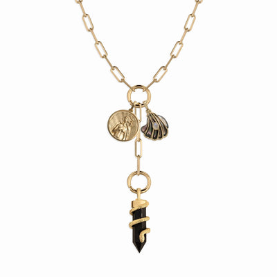 The Dark Waves Charm Lariat by Awe Inspired is a stunning necklace that boasts multiple charm links on an ornate gold chain. It features three beautiful pendants: a coin with a face, a scallop shell, and a black pendant wrapped in gold, evoking the mystery of dark ocean waves.