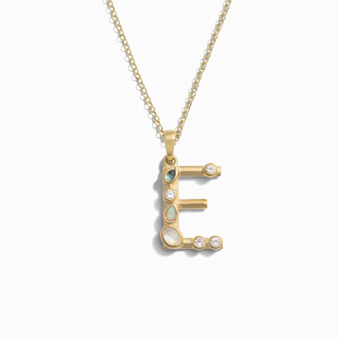 Awe Inspired's Gold Gemstone Initial Necklace features a statement-sized "E" pendant adorned with various small bezel set gemstones.